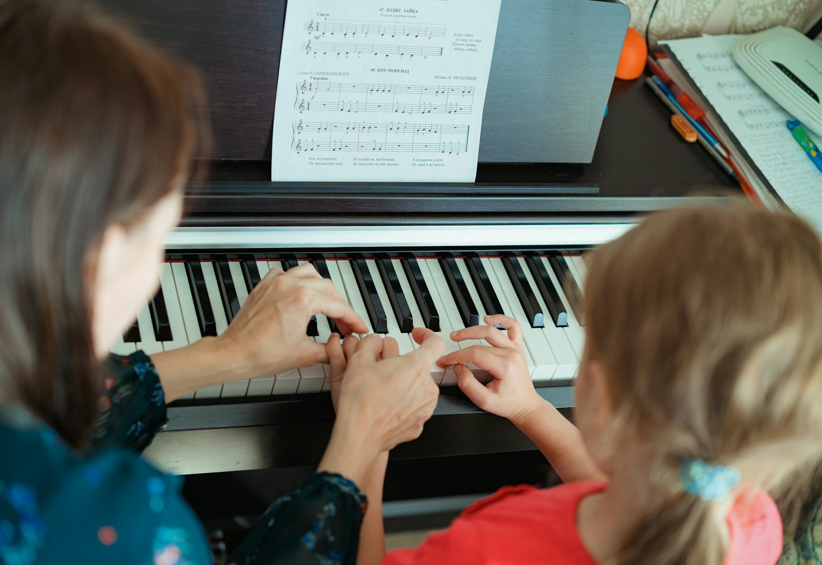 Professora e aluna a tocar piano lado a lado numa aula