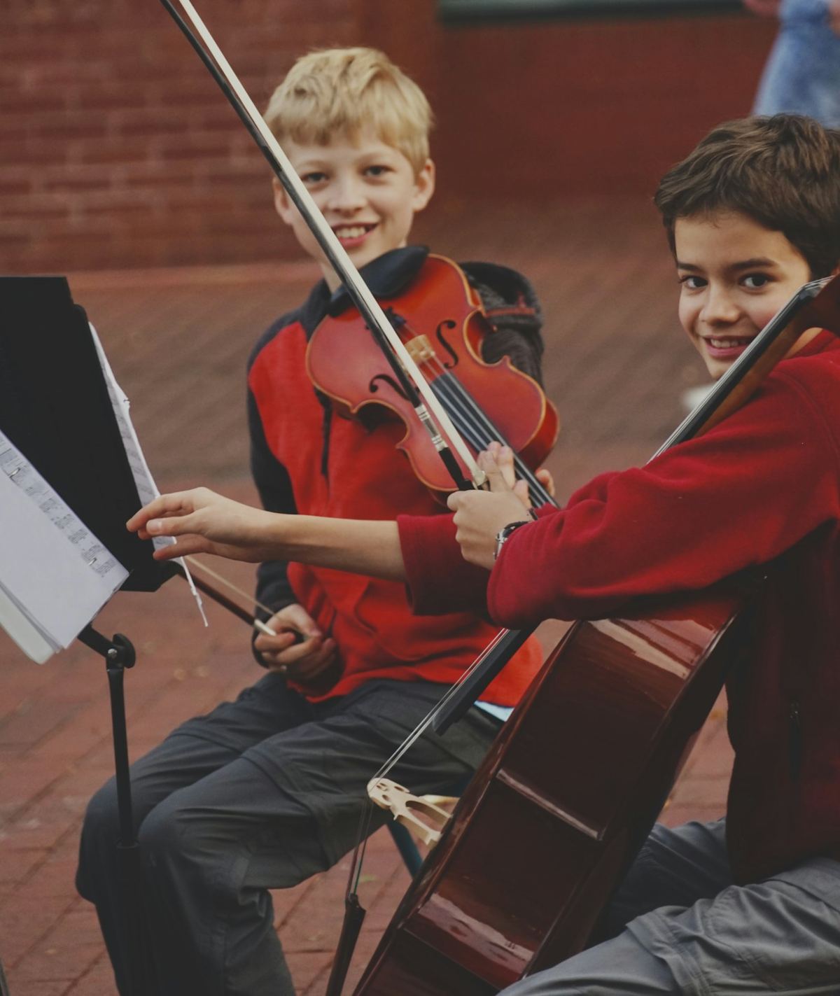 Dois rapazes sorridentes com um violino e um violoncelo